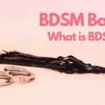 A pair of handcuffs and black flogger lay on a pink background. The text is BDSM Basics: What is BDSM?