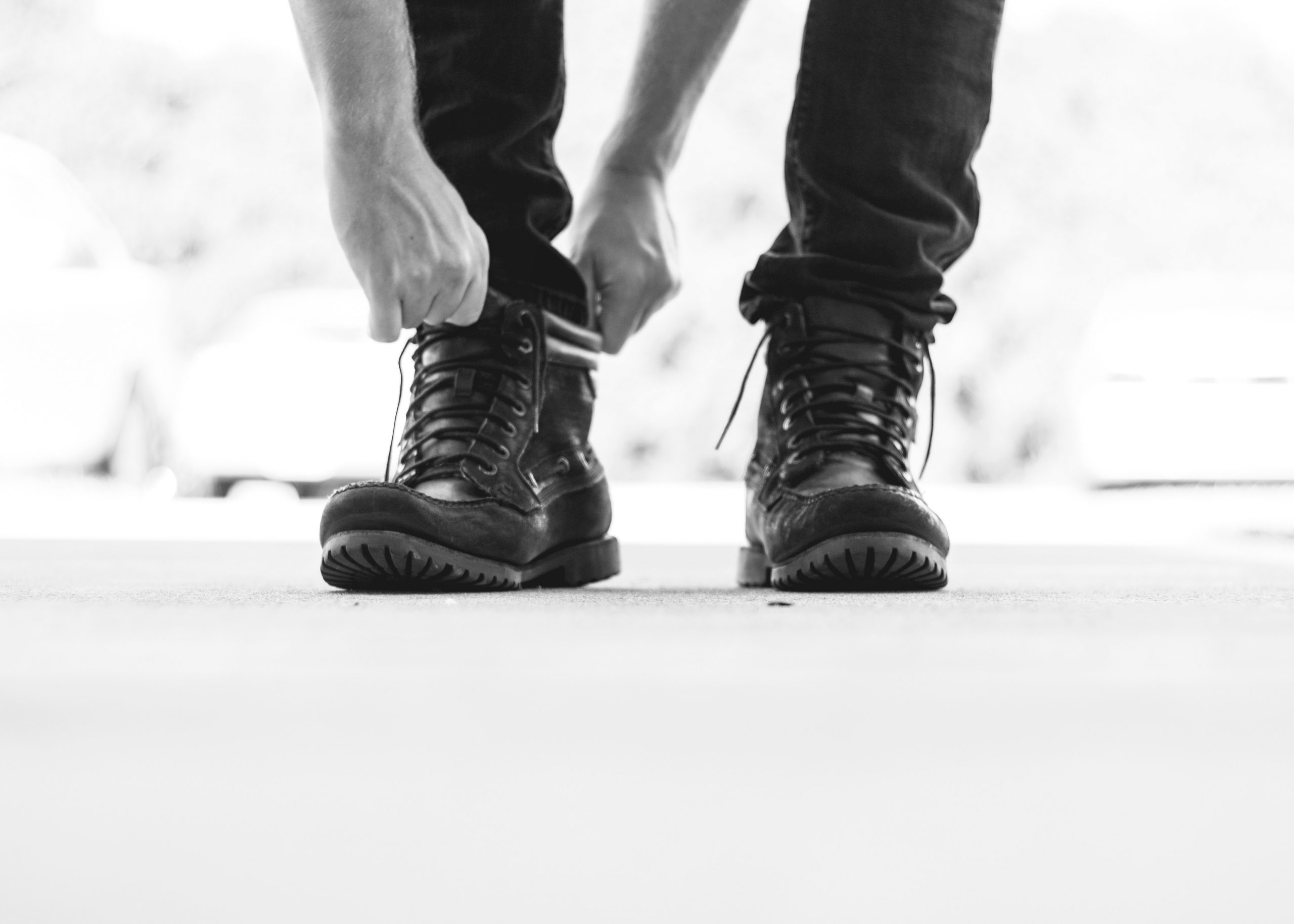 black and white picture of a man tying his boots, focused on the boots